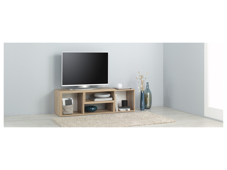 Un meuble TV avec un téléviseur à écran plat, des livres et de la décoration.