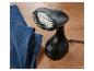Un défroisseur vapeur portatif noir avec une tête de brosse et un jean bleu sur un plancher en bois.