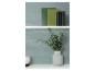 Livres verts et noirs sur l'étagère supérieure, eucalyptus dans un vase et bougie blanche sur l'étagère inférieure.