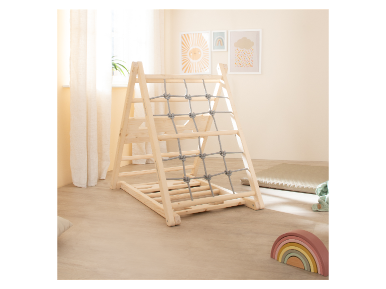 Structure d'escalade en bois pour enfants avec filet de cordes, à côté de jouets pour bébés.