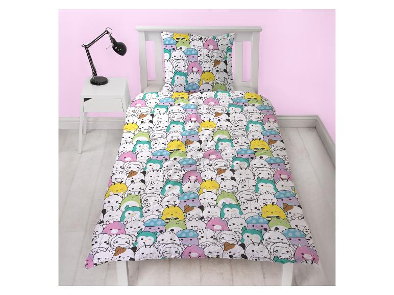 Housse de couette enfant avec des animaux colorés et cartoonesques sur un lit blanc.