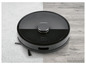 Un aspirateur robot Silvercrest noir sur une moquette et un sol en bois.