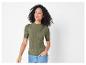 Une femme porte un haut vert côtelé à manches courtes et un jean.