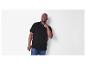 Un homme porte un polo noir.