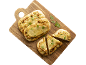Pains plats au pesto et au fromage, certains entiers et d'autres tranchés, sur une planche à découper en bois.