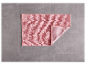 Tapis de bain rose clair sur un sol gris.