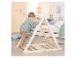 Enfant en bas âge grimpant sur une structure d'escalade en bois avec des cordes dans une chambre d'enfant lumineuse.