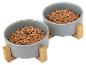 Deux bols gris pour nourriture pour chien avec des supports en bois, remplis de nourriture.