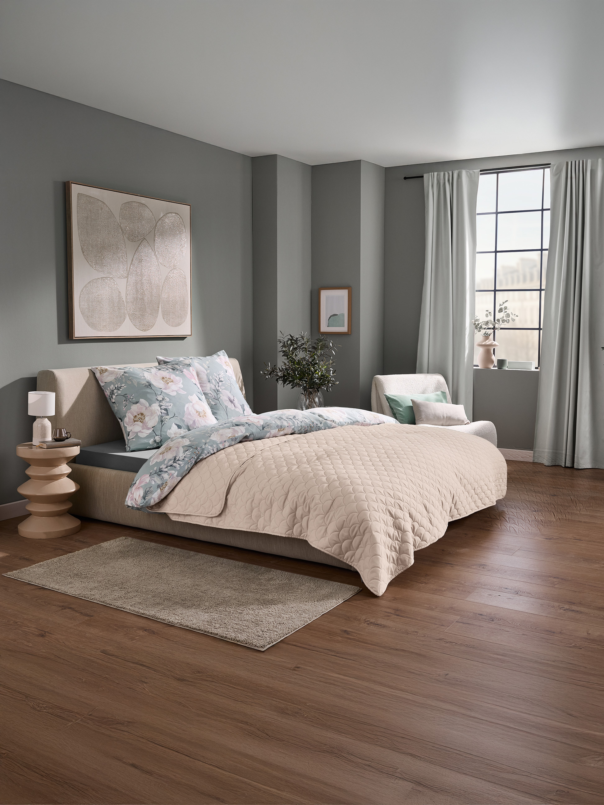 Chambre avec un lit doté d'une parure de lit florale et d'un couvre-lit matelassé beige, et une fenêtre avec rideaux.