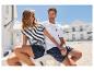 Couple en vêtements rayés et shorts marins près d'une maison blanche.
