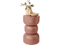 Vase beige avec eucalyptus et bol sur une table d'appoint rose à trois niveaux.