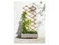 Une jardinière en bois avec des plantes vertes et un treillis contre un mur blanc.