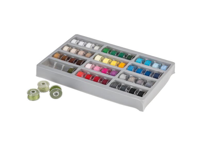 Ensemble de bobines de fil à coudre de différentes couleurs, rangées dans une boîte grise.