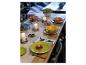 Table dressée avec des assiettes colorées, des bougies et un plat de tartare de bœuf.