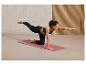 Une femme faisant du yoga sur un tapis rose.