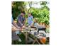 Famille préparant des pizzas dans le jardin avec un four à pizza extérieur et des accessoires.