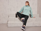 Une femme portant un sweat-shirt et un pantalon de survêtement Jette®Sport assise sur des marches en béton.