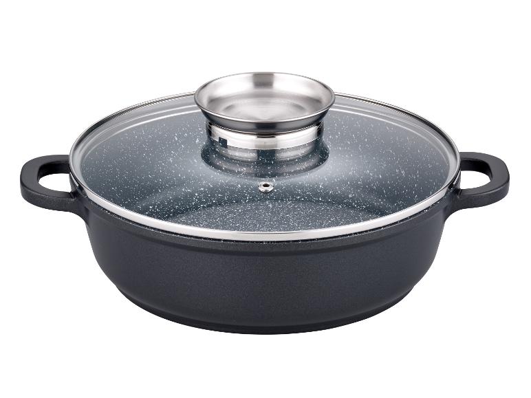 Une casserole noire avec un couvercle en verre transparent et des poignées en acier.