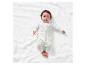 Bébé sur un tissu blanc portant un pyjama à motifs nuages.