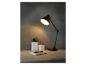 Une lampe de bureau noire avec un carnet et des stylos sur un bureau en bois.