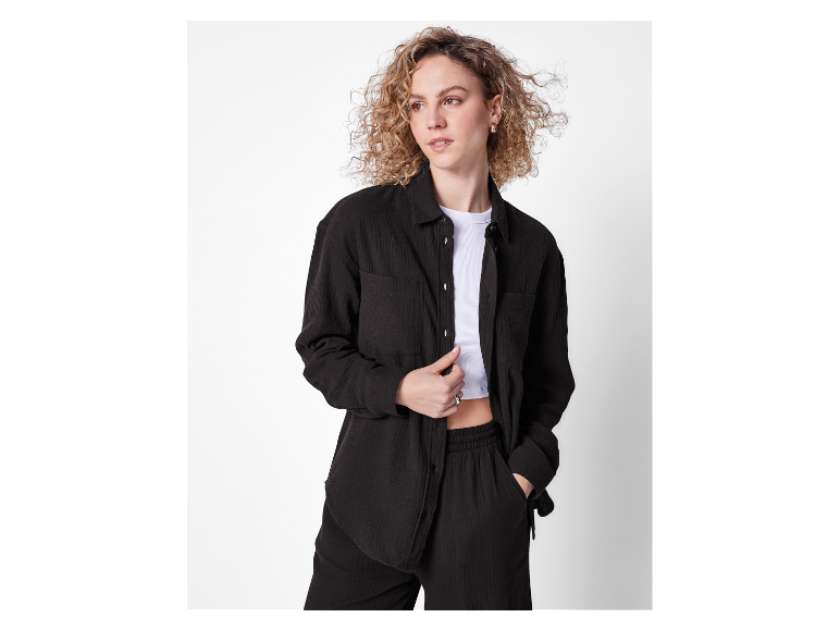 Modèle portant un ensemble pantalon et chemise noirs en coton.