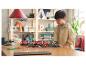 Un enfant joue avec un train et une gare LEGO City sur une table en bois.