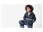 Un enfant souriant portant une veste et un pantalon imperméables bleu marine.