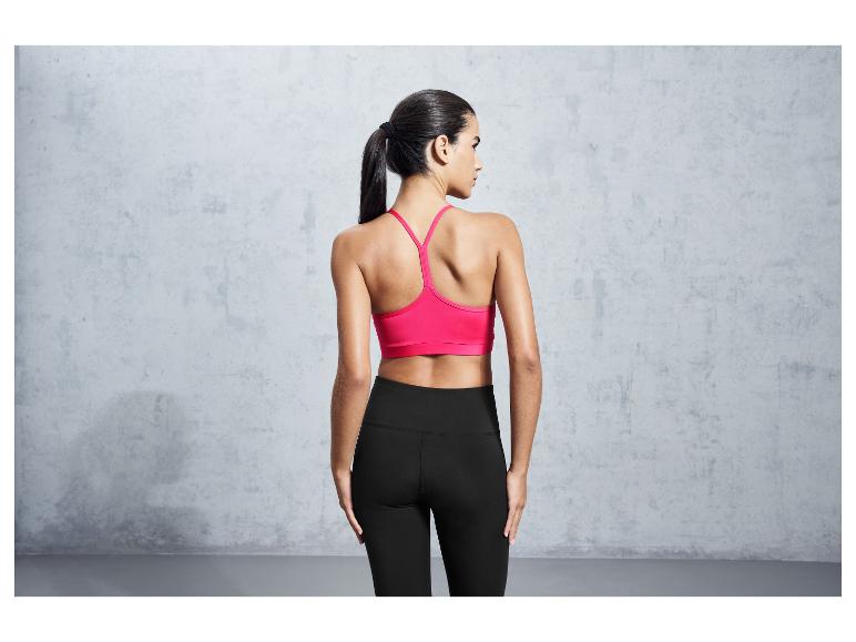 Une femme portant un soutien-gorge de sport rose et un legging noir.