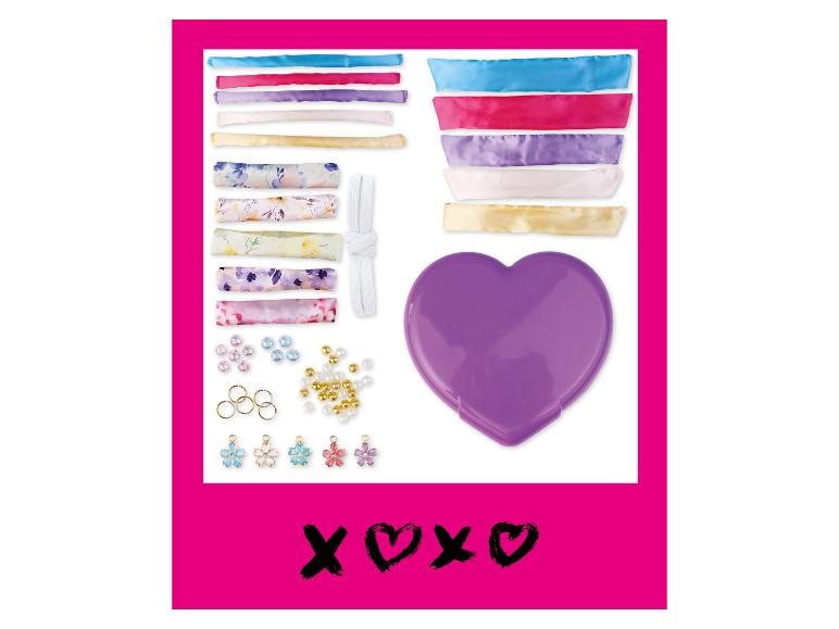 Kit de loisirs créatifs avec rubans colorés, perles, breloques fleurs et une boîte en forme de cœur.
