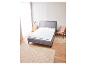 Un lit gris avec un matelas sur un sol en bois.