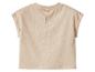 T-shirt bébé beige à manches courtes avec fermeture boutonnée au dos.