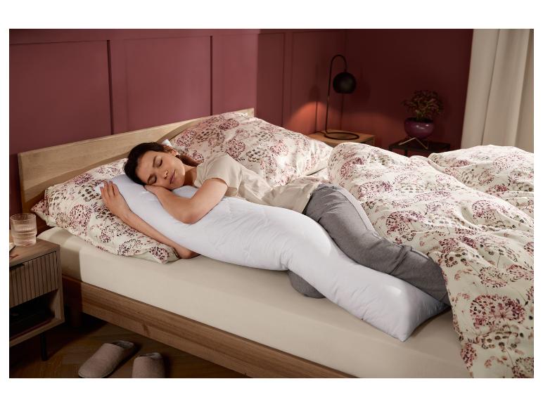 Femme dormant confortablement dans son lit avec le traversin d'allaitement LIVARNO home.