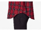 Chemise à carreaux rouge et noire avec ourlet asymétrique sur un pantalon noir.