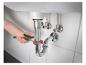 Un plombier utilise une clé à molette pour réparer le siphon d'un lavabo.