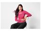 Une femme portant un pull rose et un pantalon noir.