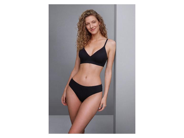 Femme souriante aux cheveux bouclés, vêtue d'un soutien-gorge et d'une culotte noirs.