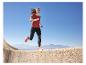 Femme courant en t-shirt rouge et legging noir, chaussures de course orange.