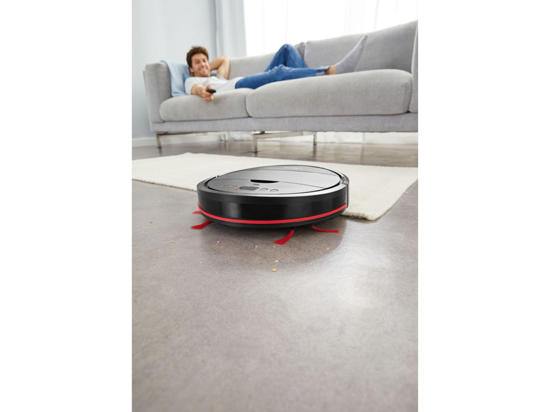 Un robot aspirateur Roomba sur un tapis dans un salon.