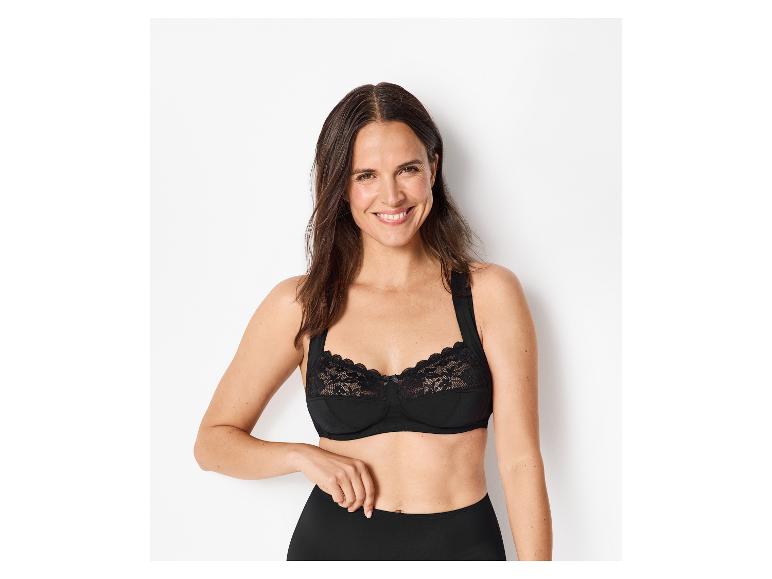 Femme souriante en soutien-gorge en dentelle noire et culotte noire.
