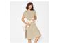 Femme en robe t-shirt beige avec une chemise blanche nouée à la taille.