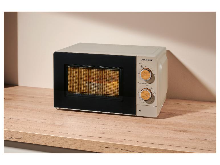 Micro-ondes beige avec panneau de commande en bois, sur une table en bois.