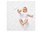 Bébé jouant avec un hochet en crochet sur un plaid blanc.