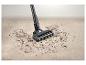 Aspirateur balai nettoyant un tapis avec des débris.