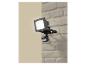 Projecteur extérieur avec détecteur de mouvement, monté sur un mur de briques.