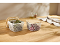 Deux paniers de rangement en maille blanche avec couvercles en bois sur un plan de travail.