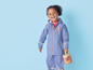 Un enfant portant un imperméable et un pantalon de pluie bleus et une arrosoir.