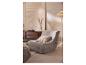 Fauteuil lounge gris matelassé avec coussin décoratif dans un salon confortable.