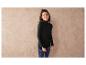 Une femme porte un pull noir à col roulé et un jean bleu.