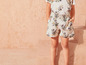 Un enfant porte un t-shirt blanc à fleurs et un short à fleurs.