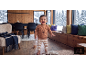 Bébé souriant en pull ours et pantalon rayé, dans un salon avec vue sur la neige.